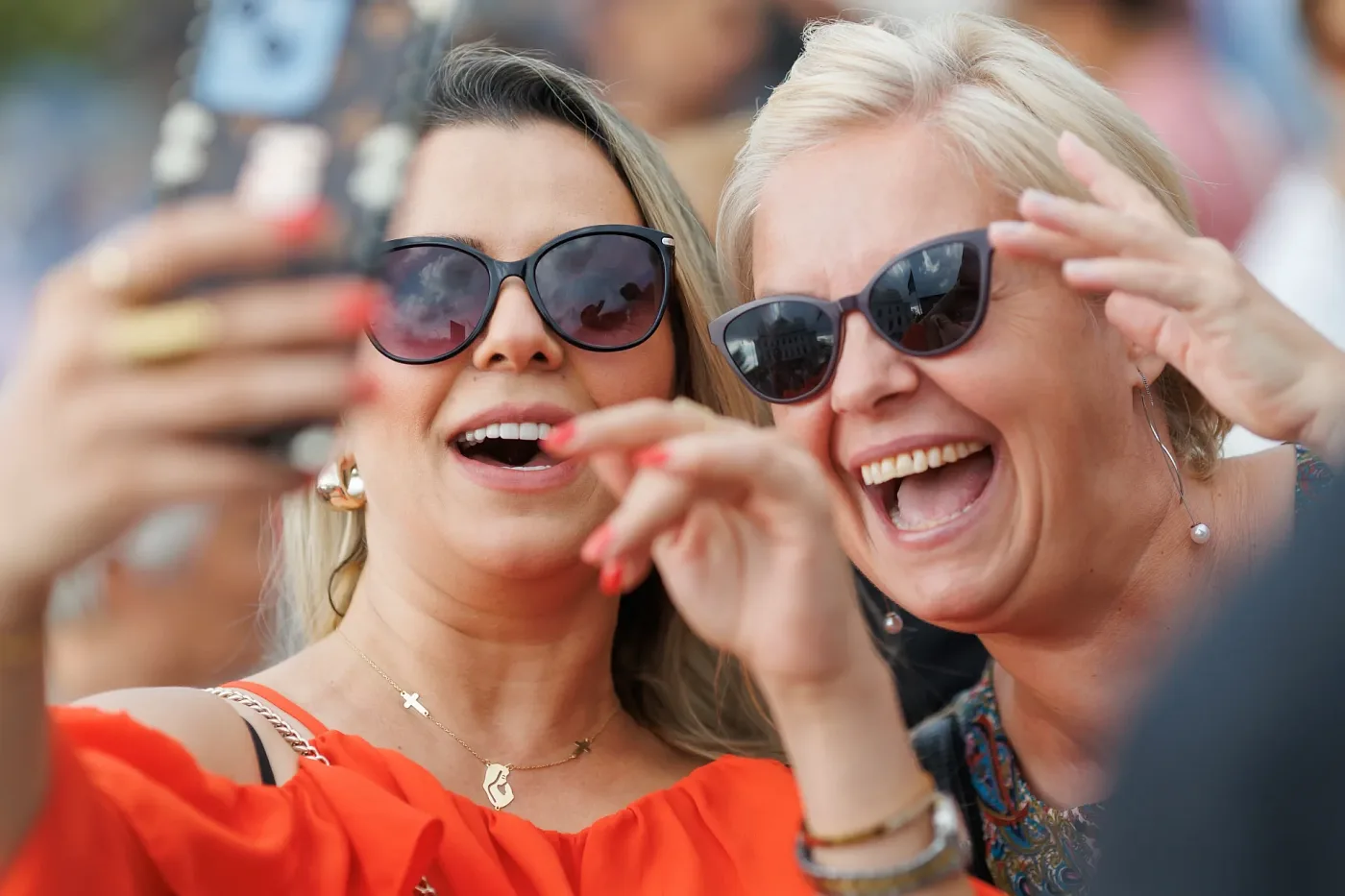 Two laughing visitors in sunglasses taking a selfie at the festival