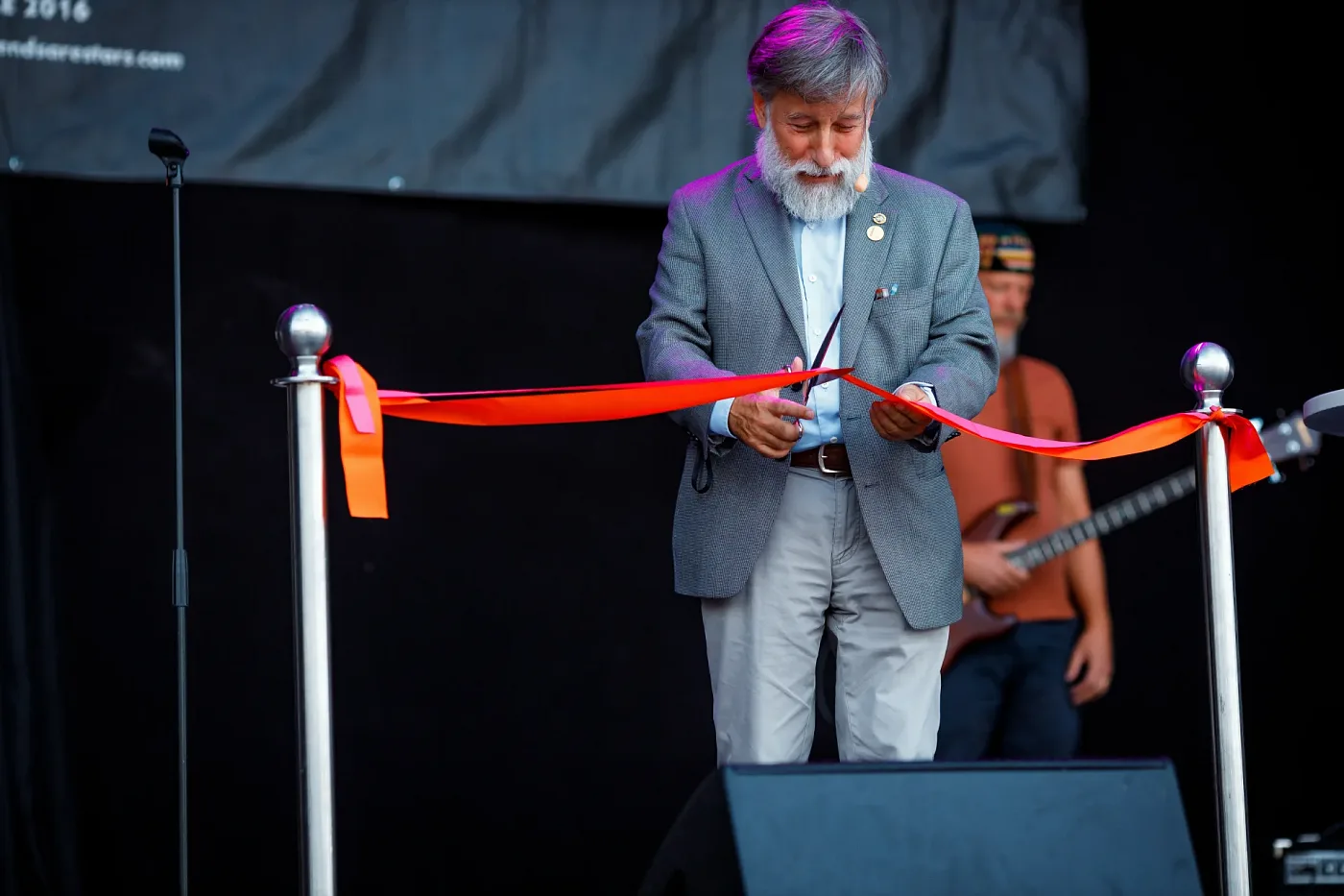 A man in a jacket cutting the red opening ribbon on the festival stage, Göteborgs Kulturkalas 2023