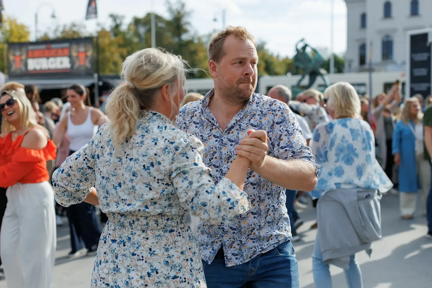 A couple dancing on the asphalt in front of the stage, more dancers behind them