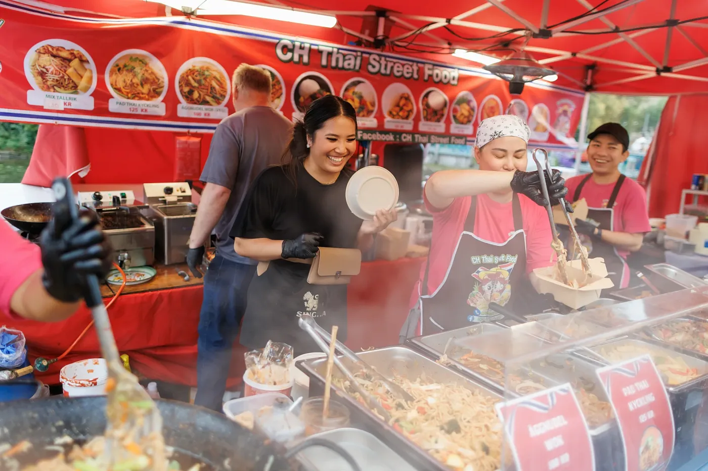 Staff in a street food stall serving noodles to a guest