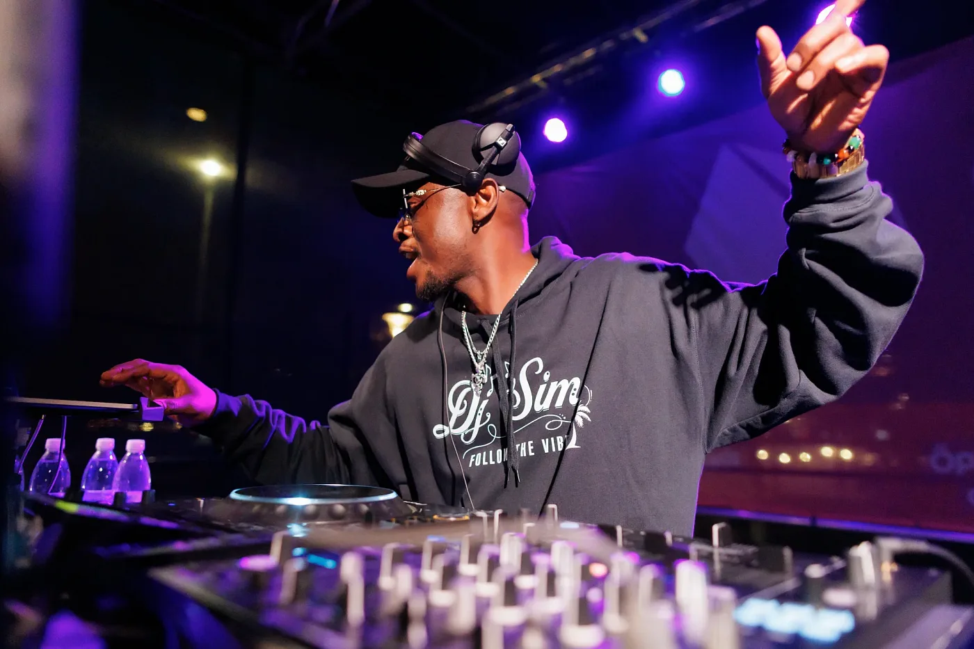 A DJ behind the mixing desk on an evening stage in purple spotlights