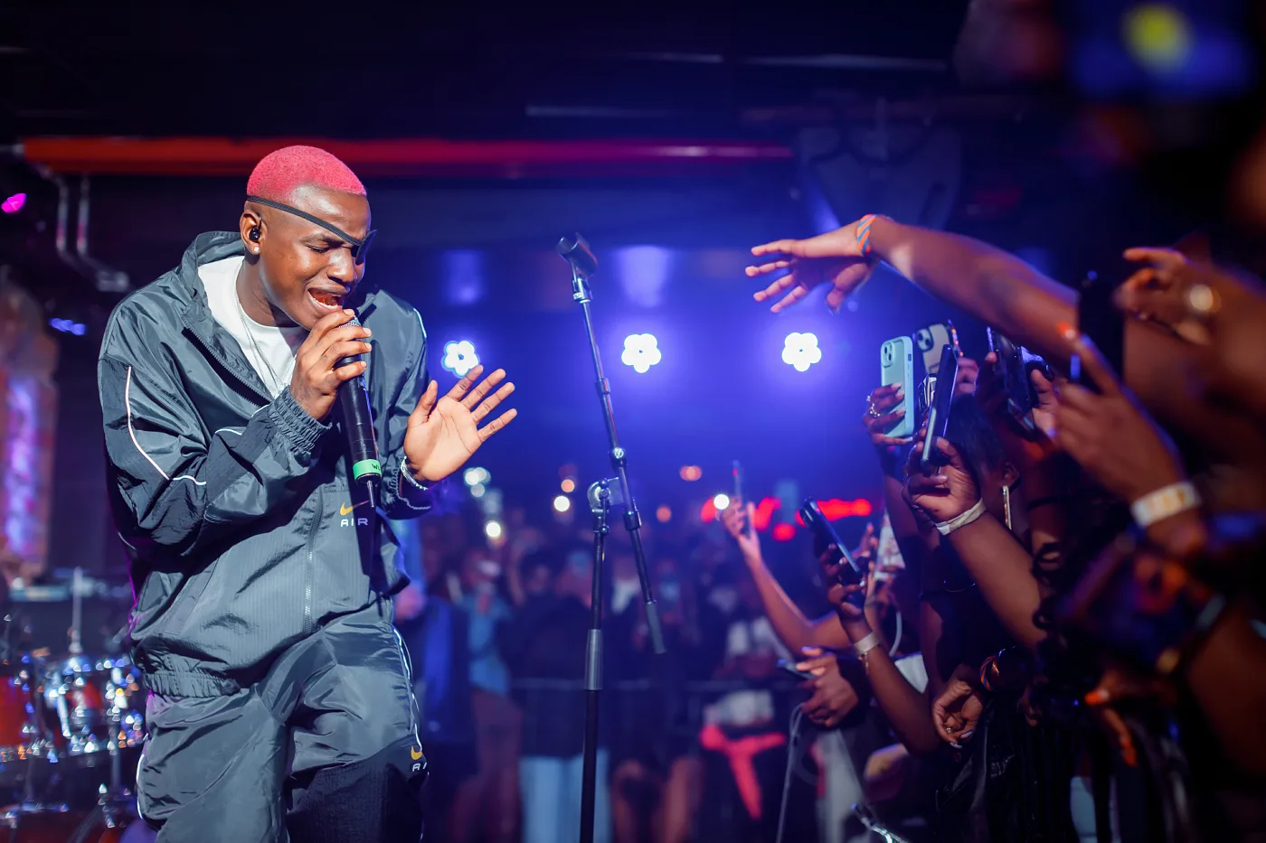 An artist with a microphone at the edge of the stage at Nefertiti, fans reaching out, Gothenburg