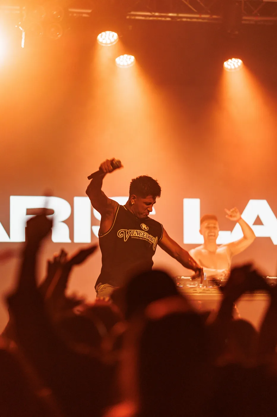An artist on stage at Vulkan Arena in orange light, the crowd reaching up, Oslo