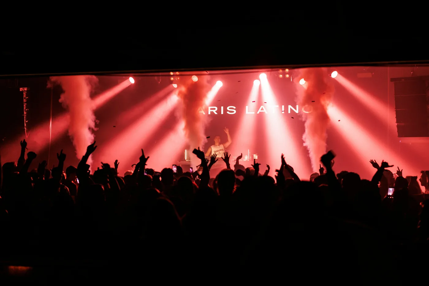 The Vulkan Arena stage in red light and a crowd with raised hands, Oslo
