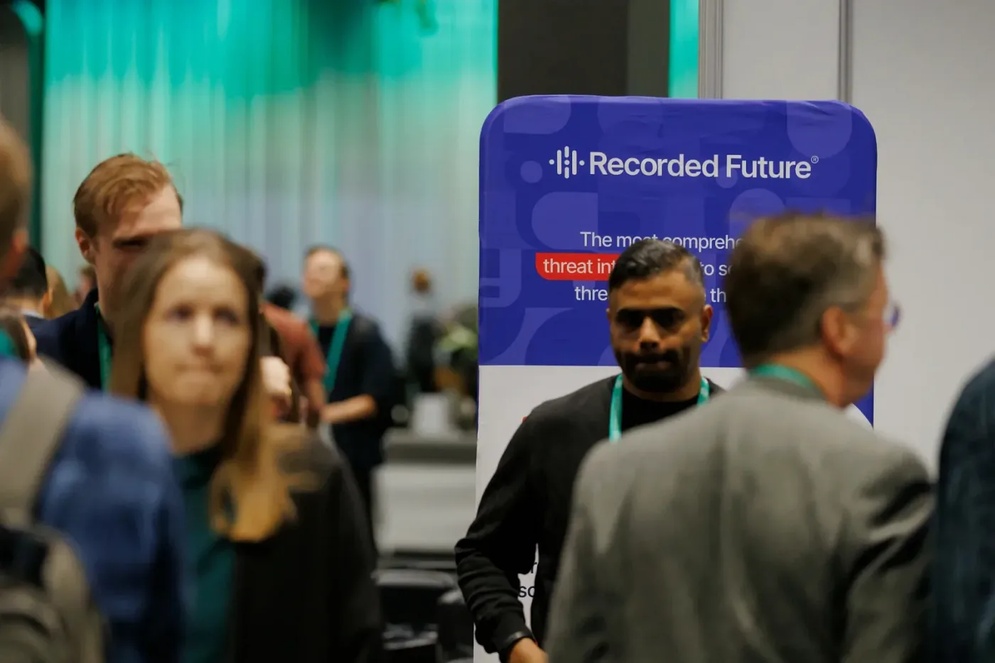 Attendees walking past a partner roll-up banner in the exhibition area