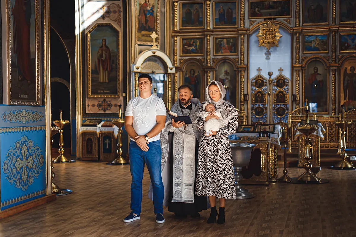 Godparents with the priest in church before the christening