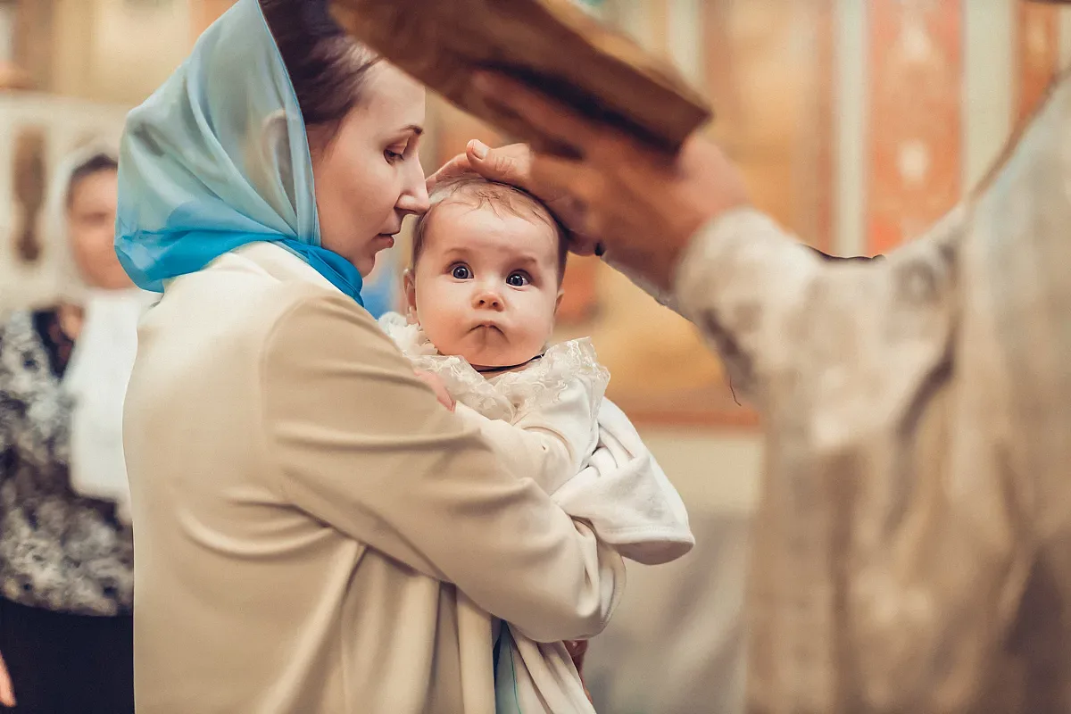 The priest reads a prayer over the baby in the mother’s arms