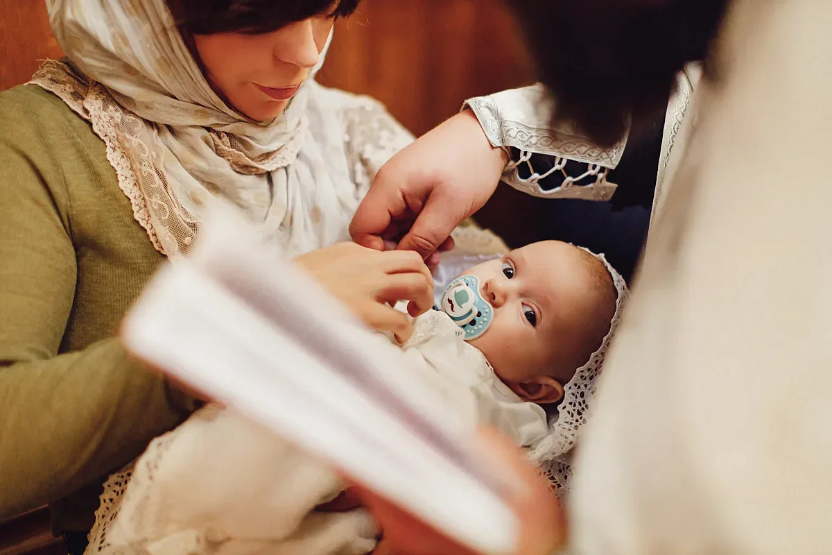 Godmother reading a prayer with the baby in her arms