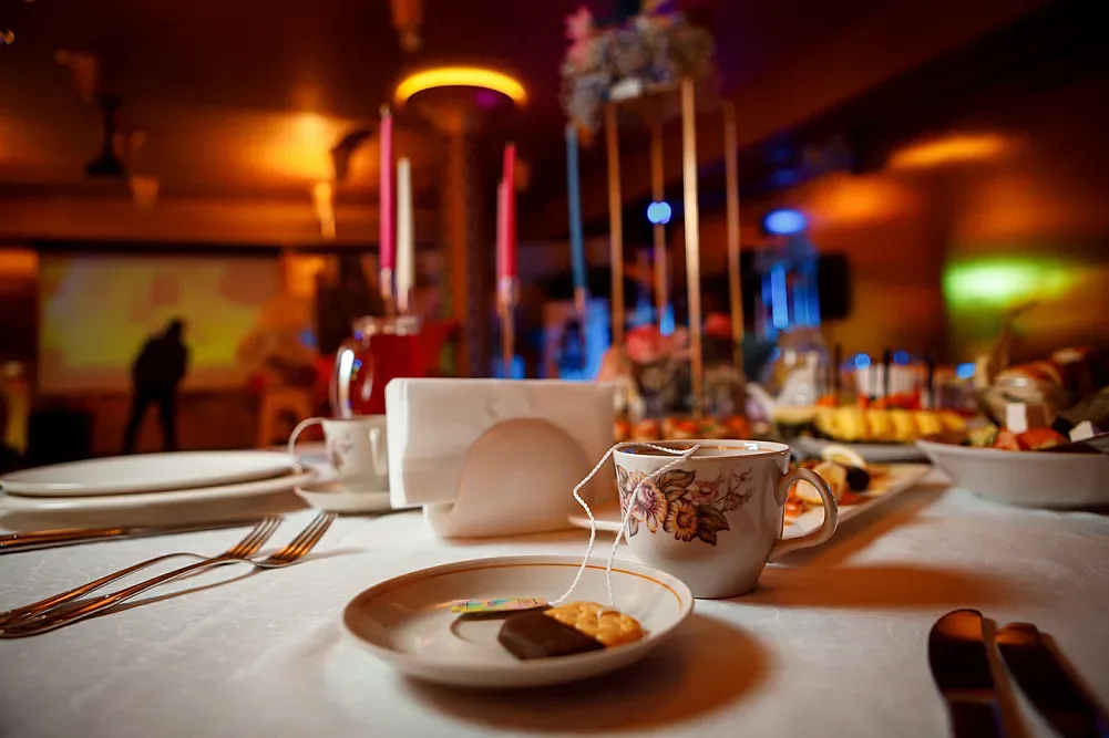 Detail of the laid table: dessert, coffee cups and decor in warm light