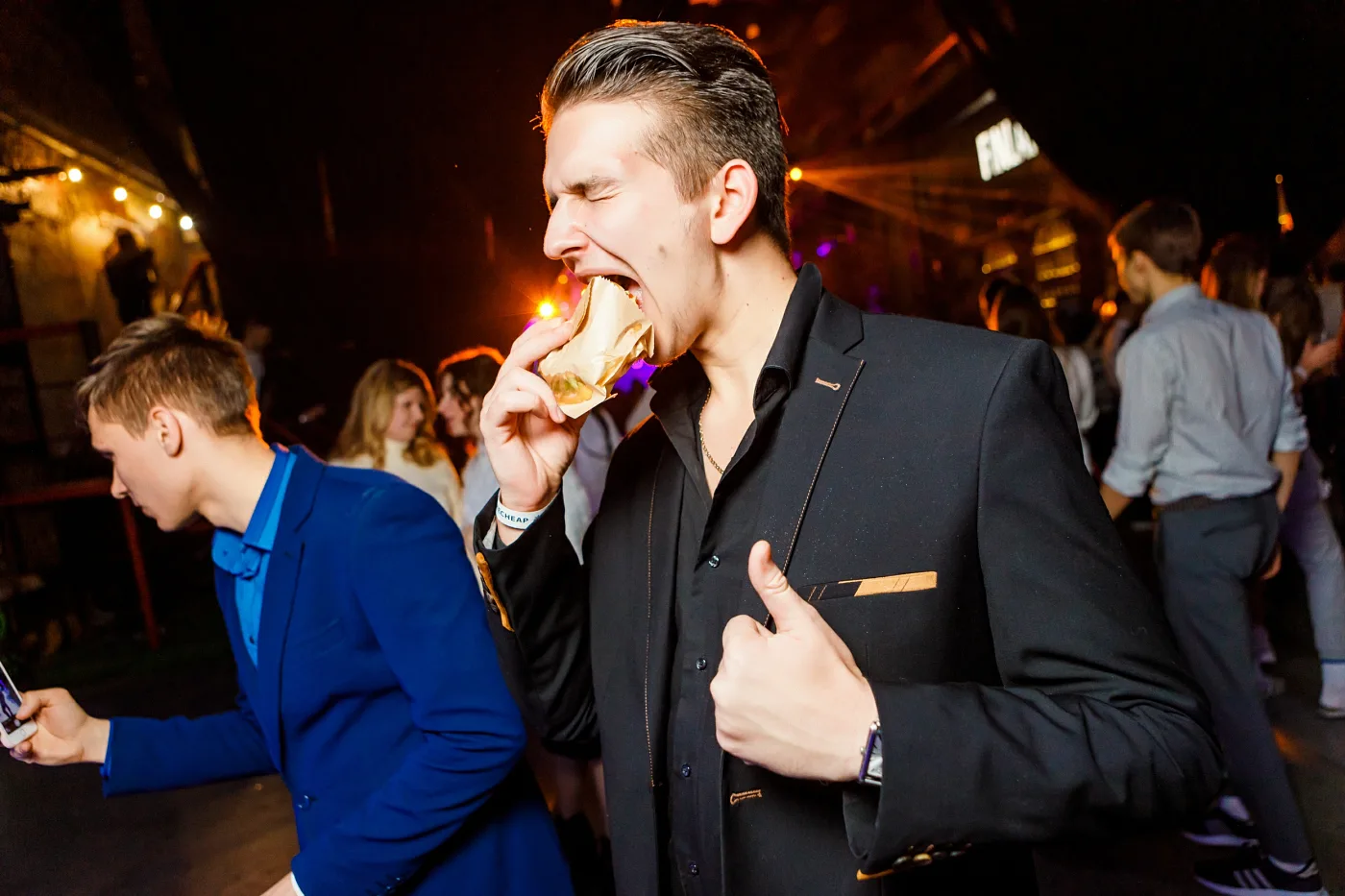 A guest with a snack in hand giving a thumbs up on the dance floor