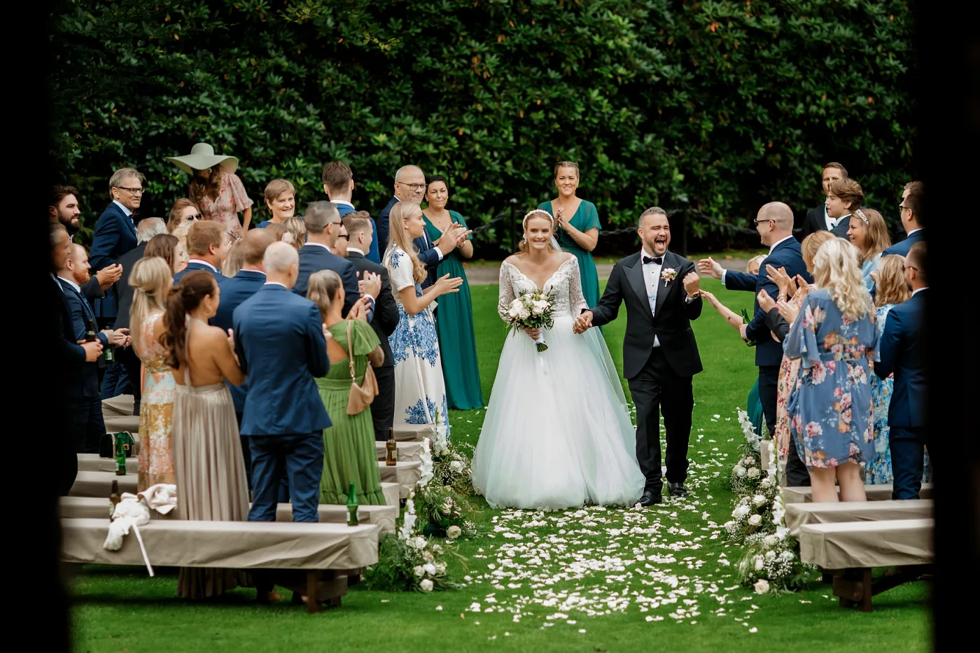 The couple walking down the petal-strewn aisle as the guests stand and applaud
