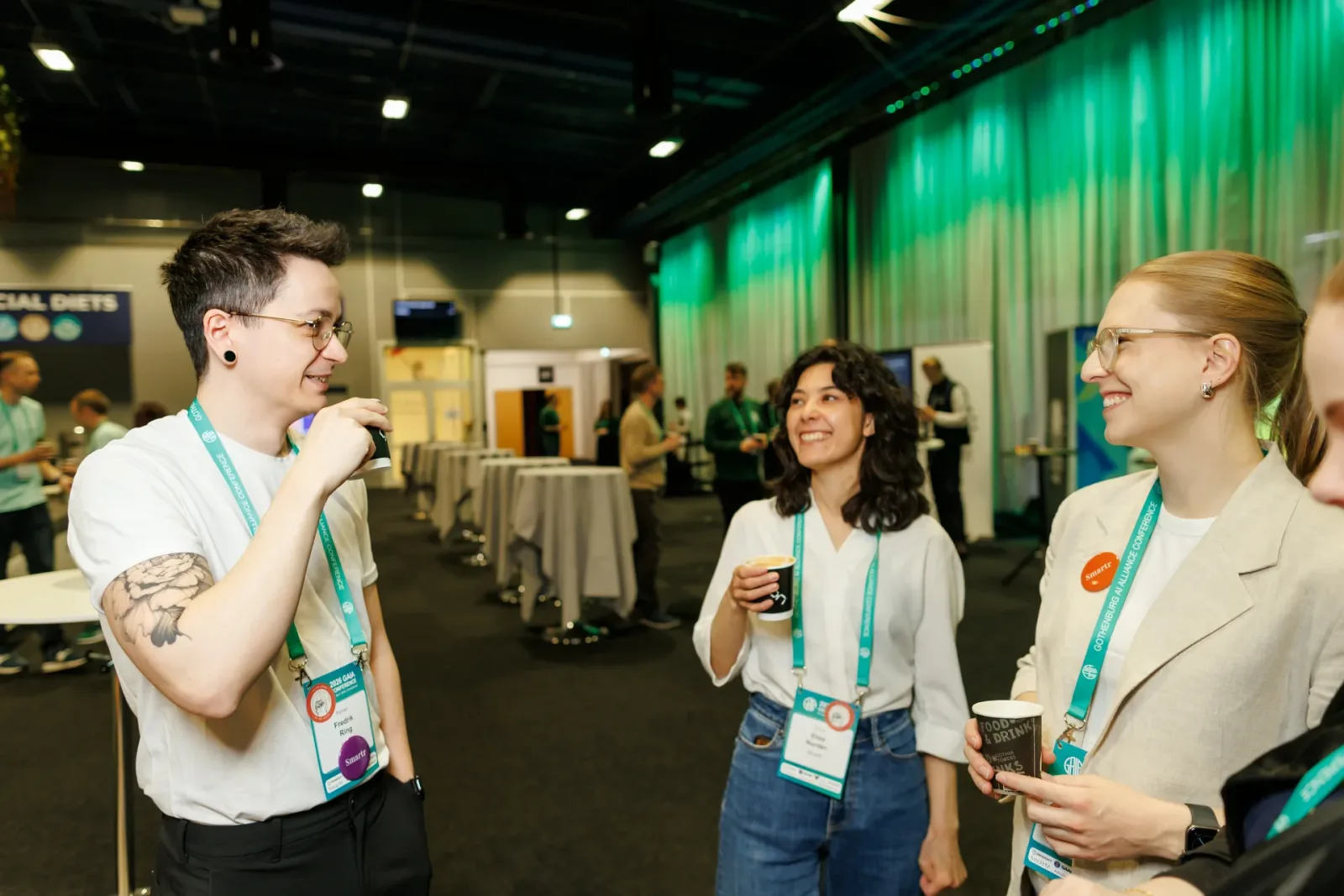 Three conference attendees with coffee talking in the break