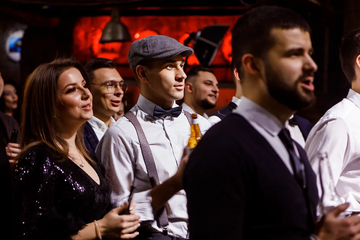 Smiling party guests in suits and a flat cap at an evening party