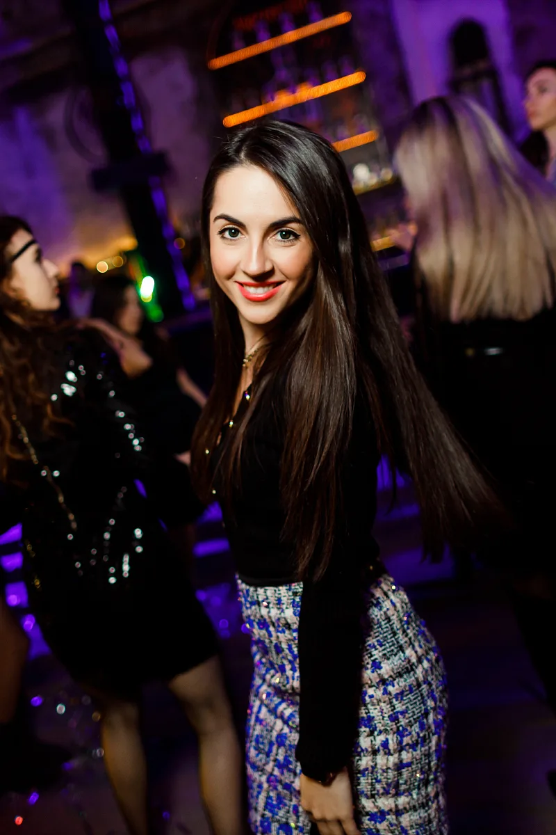 Woman with long dark hair smiling in coloured club light