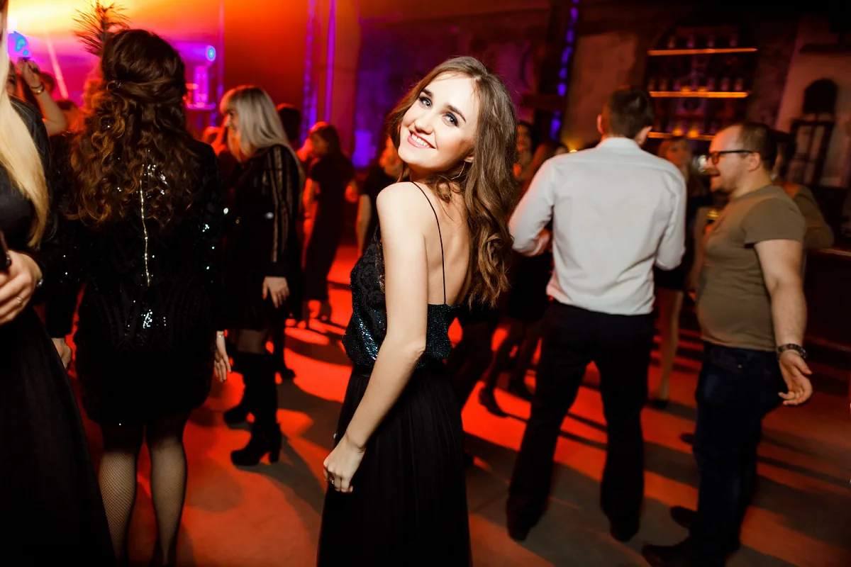 Young woman in a black dress looking over her shoulder on the dance floor