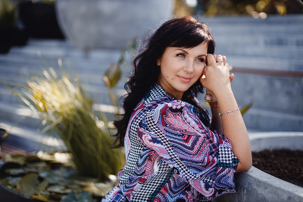 Woman in a bright dress sitting by the water and smiling