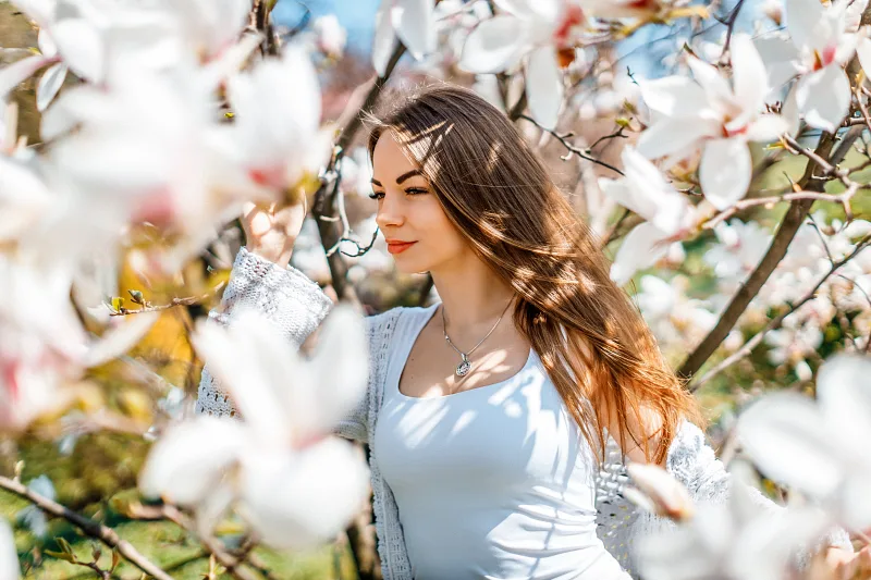Woman in a white top among blooming magnolia