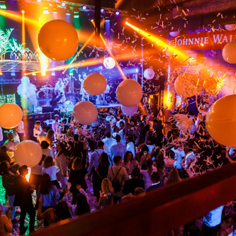 Wide-angle photo of a corporate conference event with attendees networking and engaging with speakers