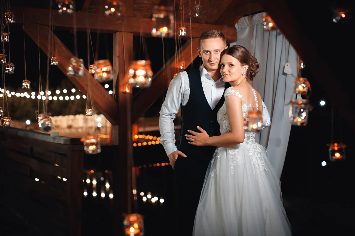 Bride and groom under string lights and lanterns at the evening party