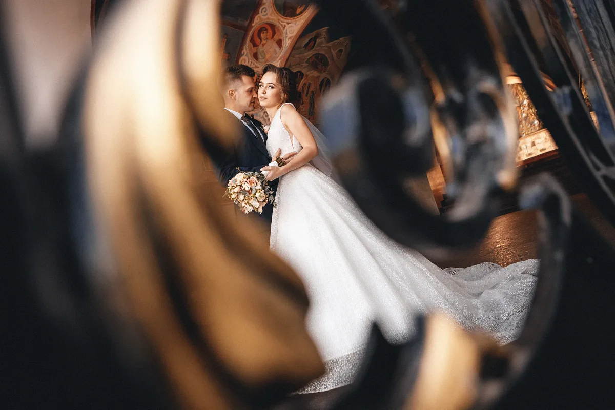 Bride and groom framed by gilded ornaments in a hall