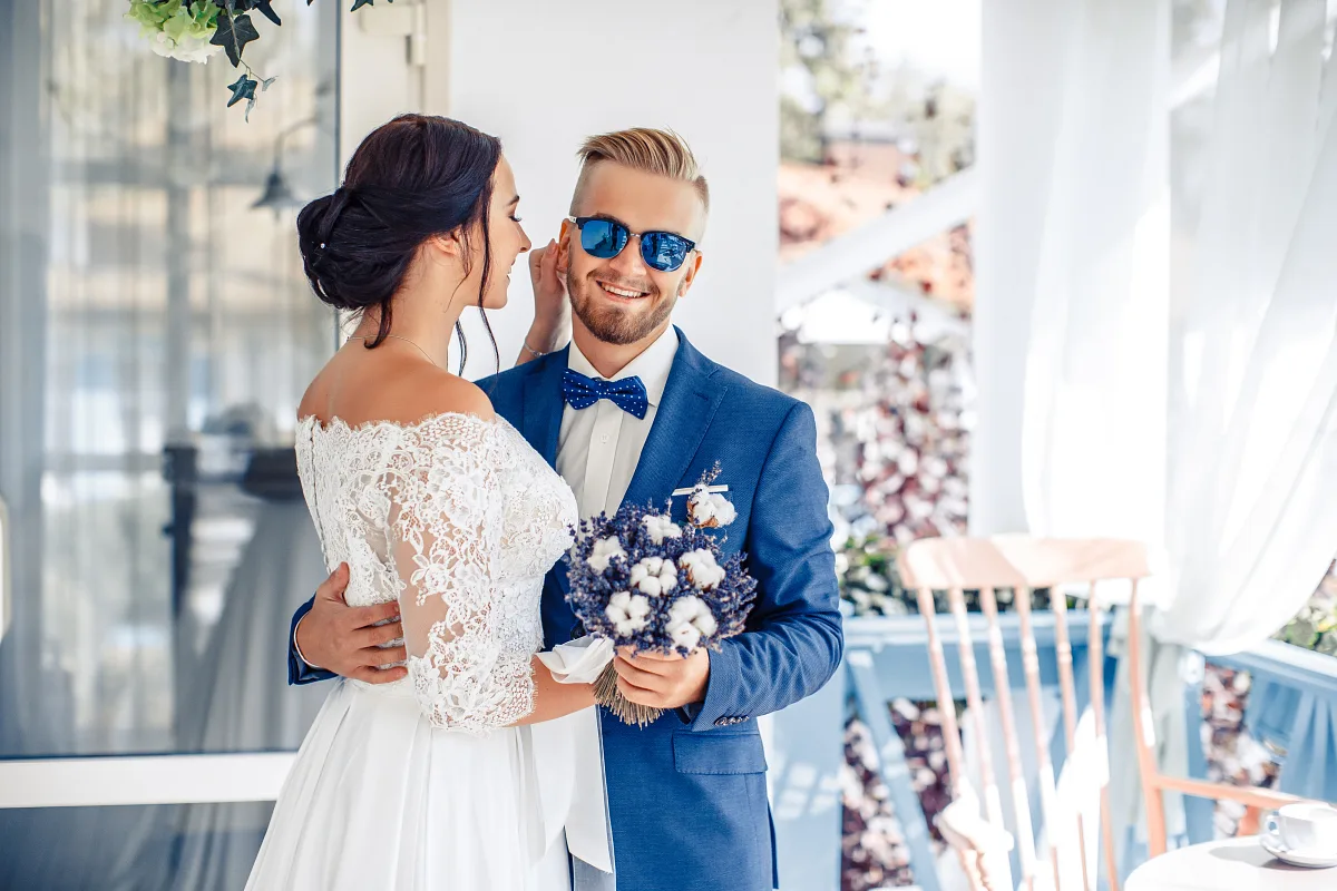 Bride and groom smiling at each other, bouquet in hand